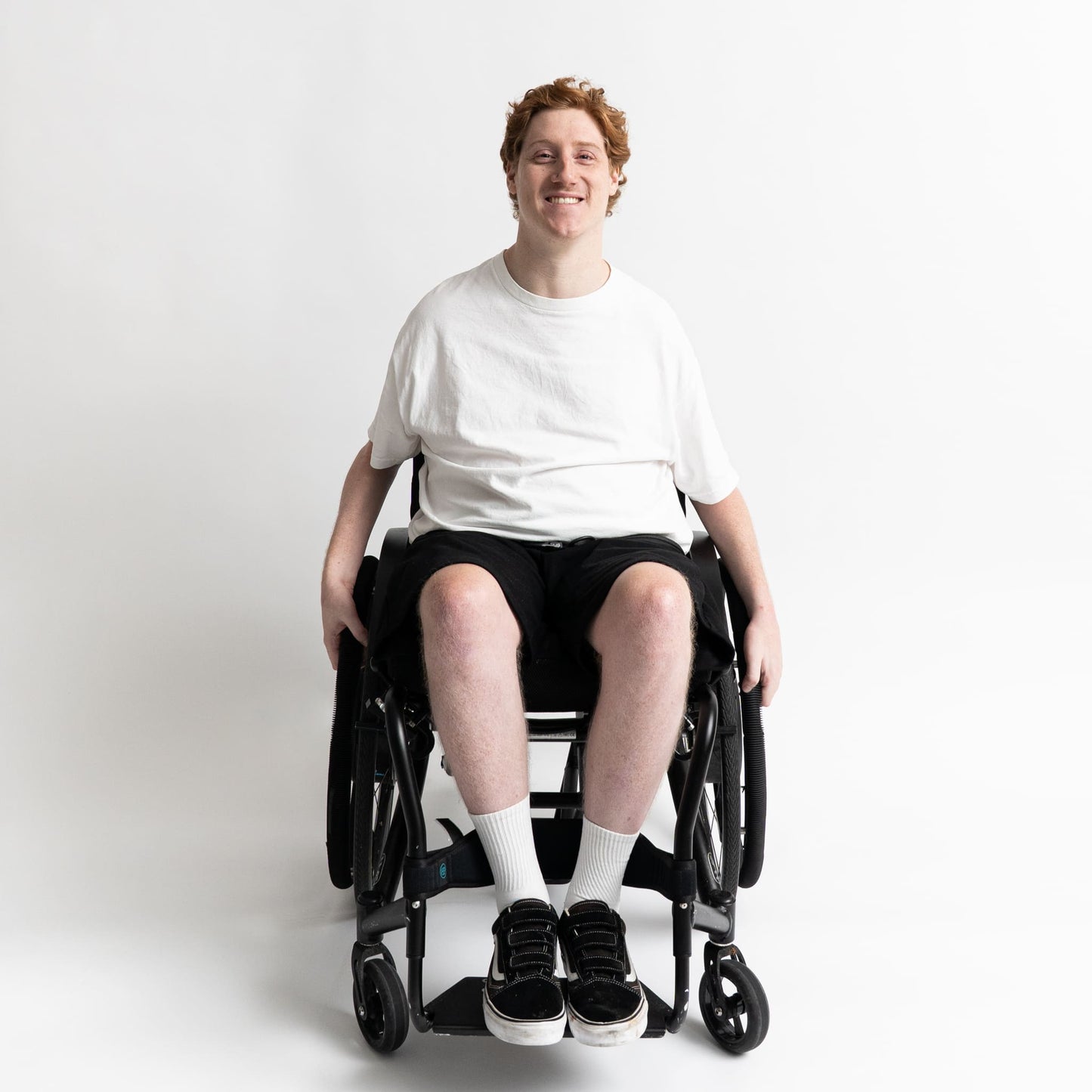 “Model seated in a wheelchair wearing adaptive cotton shorts with elastic waist and front-access pockets.