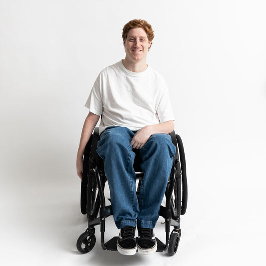 “Wheelchair user wearing adaptive stretch denim jeans with elastic waist and accessible front pockets.”

